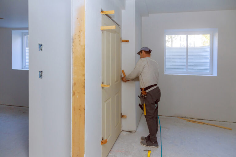 Handwerker richtet Zimmertür beim Einbau aus – präziser Türeneinbau im Innenausbau.