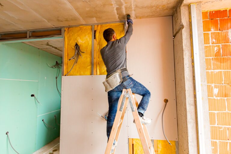 Handwerker montiert Trockenbauplatten im Innenausbau – Bauarbeiten mit Gipskarton und Dämmung im Rohbau.