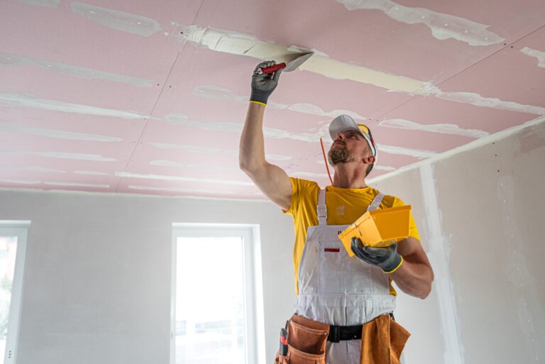 Handwerker verspachtelt Decke mit Spachtelmasse im Innenausbau.