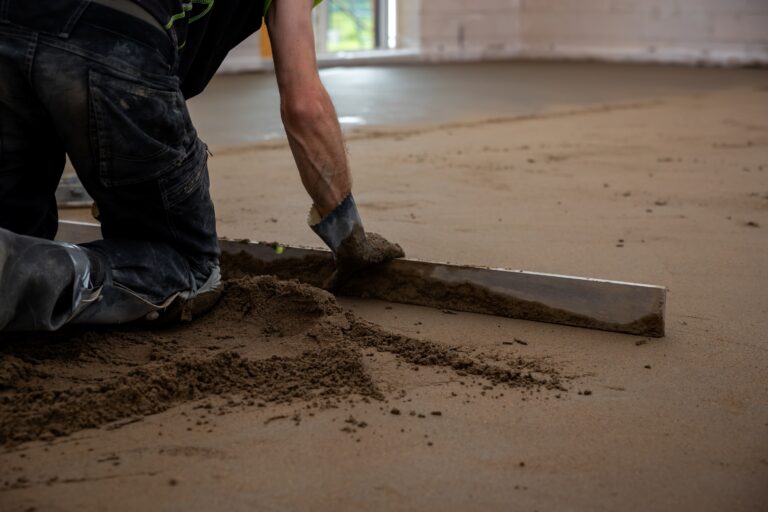 Handwerker glättet Estrichboden im Innenausbau – präzize Schüttdämmung Bodenarbeiten im Rohbau.