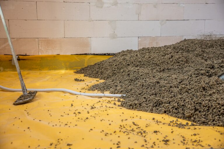 Trockenschüttung verlegen: frischer Estrich auf gelber Baufolie im Neubau.
