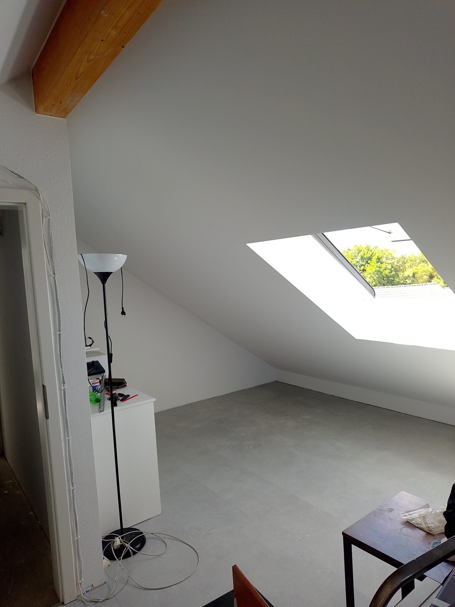 Ausgebauter Dachraum von SN mit hellen Oberflächen, sichtbarem Holzbalken und Dachfenster